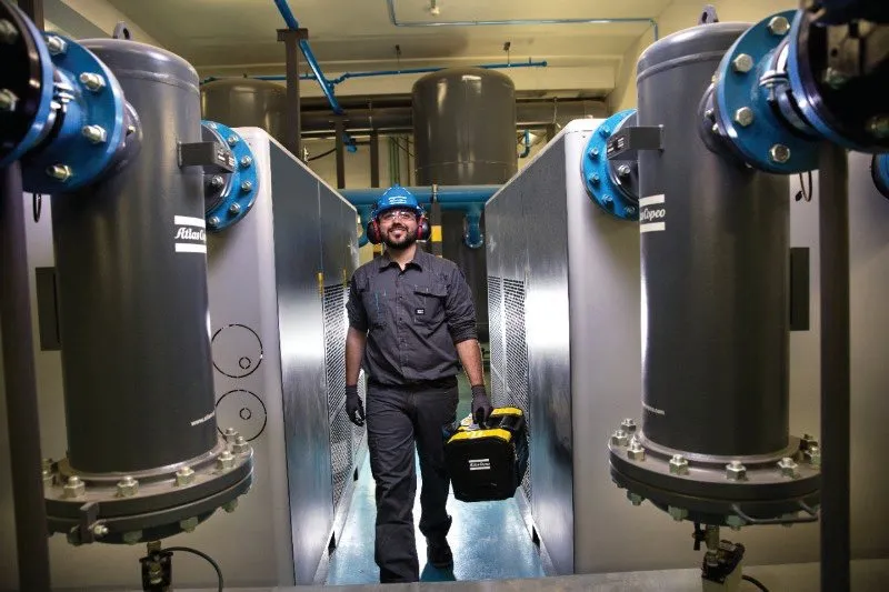 En tekniker går mellem kompressorer (foto: Atlas Copco)